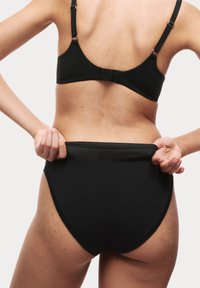 Zwarte bh met dunne verstelbare bandjes en haaksluiting. Zwarte hooggesneden onderbroek, gladde stof, met elastische tailleband en beenopeningen.