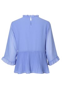 Ljusblå blus med volangdetaljer vid halsringningen, pliserad nederkant och trekvartslånga ärmar med volangdetaljer. Nyckelhål i ryggen.
