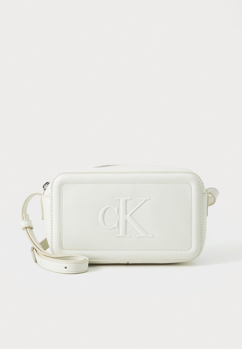 Borsa a tracolla in pelle bianca con forma rettangolare, logo "cK" in rilievo, chiusura con zip e tracolla regolabile. Texture liscia e design minimalista.
