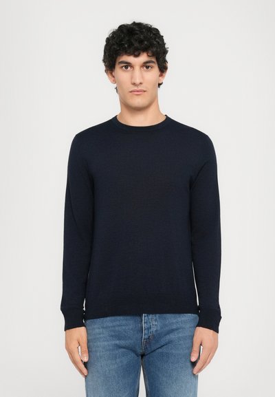 Dark navy crewneck sweater in a soft knit, featuring long sleeves and a fitted hem, paired with light blue denim jeans.