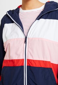 Kolorowy, blokowy kurtka z kapturem w odcieniach granatu, bieli, różu i czerwieni, z zapięciem na zamek oraz lekkiej, strukturalnej tkaninie.