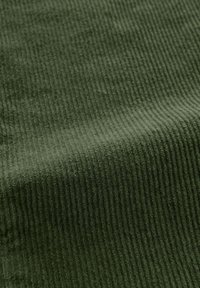 Tessuto di velluto a coste verde scuro con costine verticali prominenti, texture morbida e una leggera lucentezza, che mette in mostra un motivo di tessitura dettagliato.