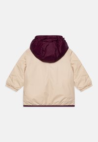 Jacket leggero beige con cappuccio bordeaux, polsini e orlo elasticizzati, e una texture liscia. Design semplice e funzionale senza abbellimenti.