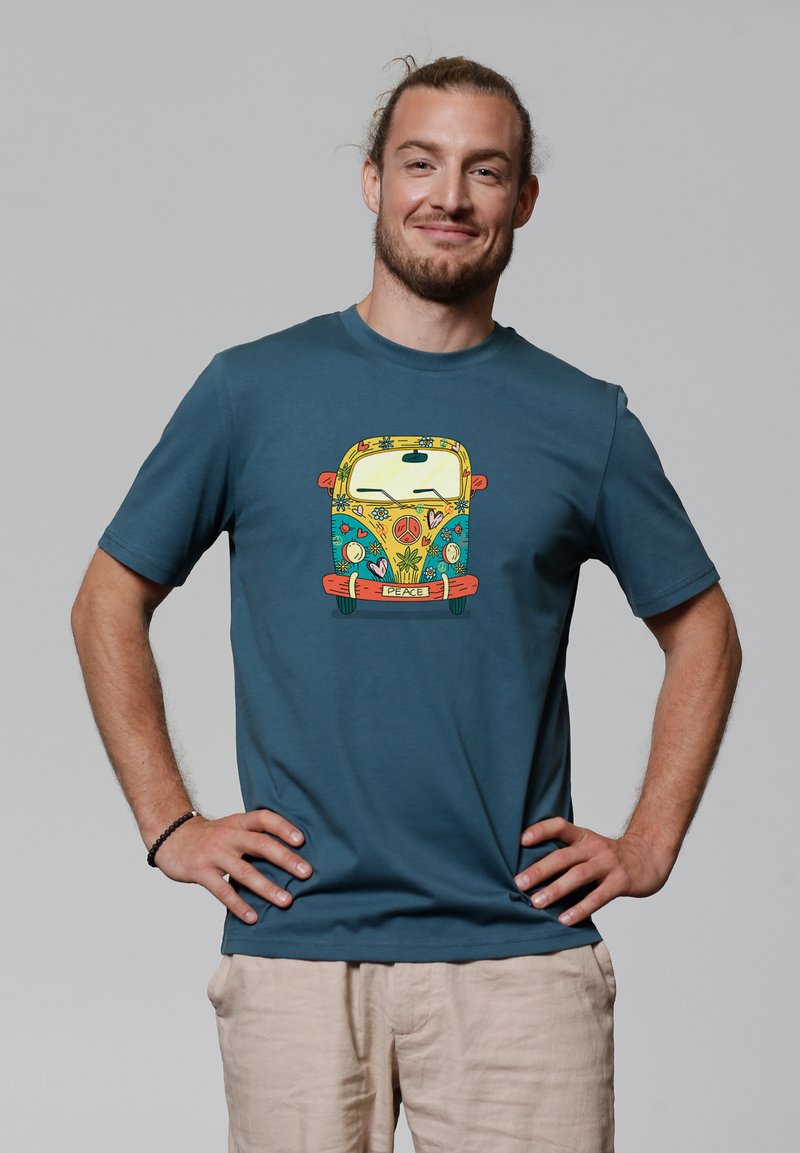 T-shirt en coton bleu avec un graphique coloré d'une vieille camionnette portant un slogan "paix", sur un fond neutre.