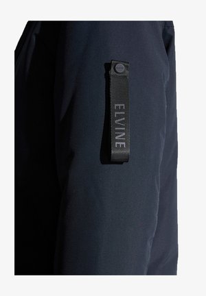 Dunkelblazer aus glattem Stoff, mit einem auffälligen schwarzen Markendetail am Ärmel, das ein modernes Designelement bietet.