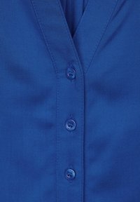 Camicia blu con scollo a V e una fila di quattro bottoni coordinati, realizzata in tessuto liscio con una leggera texture.
