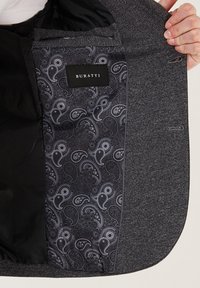 Szara teksturowana podszewka kurtki, z czarną wyściółką w wzór paisley. Posiada metkę z napisem "BURATTI" oraz gładką fakturę materiału.