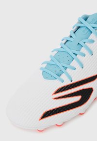 White sports shoe with textured upper, light blue laces, black and orange logo, and pink outsole studs. Features perforated detailing.