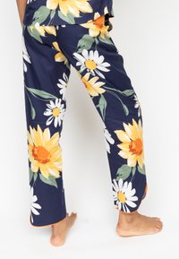 Floral pajama pants with a navy background, featuring large yellow sunflowers and white daisies. Elastic waistband and orange trim at cuffs.