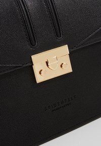 Borsa a tracolla nera con texture, dotata di una chiusura dorata e di borchie esagonali. Presenta una finitura liscia e un logo del marchio impresso sulla parte anteriore.