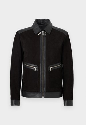 Chaqueta de ante negra con cuello de cuero, parches en los hombros, puños, borde inferior y dos bolsillos frontales con cremallera, con cierre central de cremallera.