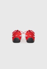 Scarpe sportive rosse con tomaia in rete e suede, lacci e suola in gomma nera. Presentano dettagli bianchi e il logo sulla parte posteriore.