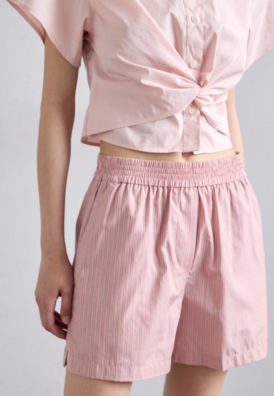 Lichtroze button-up shirt met een gedraaide voorkant, gecombineerd met roze gestreepte shorts met een elastische tailleband en kleine zijsplitten.