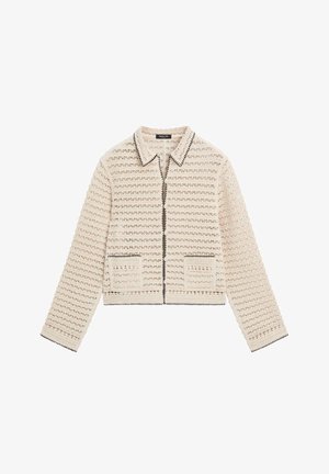 Beige gehäkelte Strickjacke mit langen Ärmeln, zwei Fronttaschen und schwarzem Besatz am Kragen, an den Taschenrändern, den Bündchen und der Reißverschlusslinie.