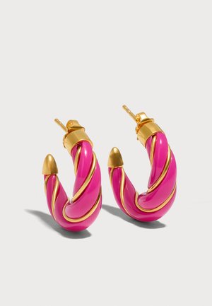 Paire de boucles d'oreilles créoles torsadées roses avec accents dorés et fermoirs à clous sur fond clair uni.