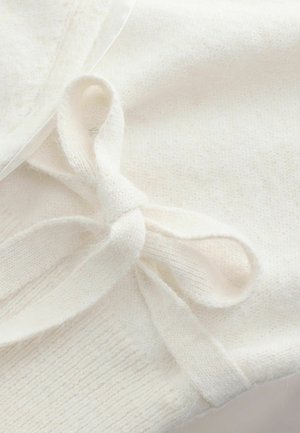 White knitted fabric features a soft texture with a bow detail made from the same material, showcasing delicate craftsmanship and minimal design.