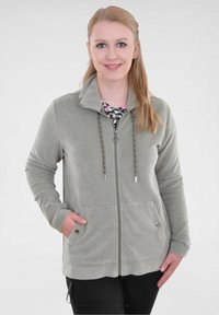 Lichtgrijze ribfluwelen ritsjack met een hoge kraag, trekkoord en twee voorzakken. Gegevensde stof en bijpassende manchetten.