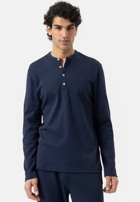 Helleblaue Langarm-Henley-Shirt aus weichem Stoff, mit rundem Halsausschnitt und drei Knöpfen, sowie enganliegenden Bündchen, kombiniert mit passenden Hosen.