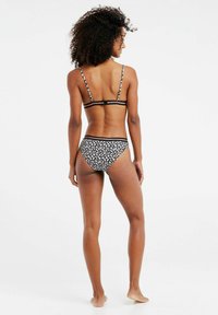 Czarny bikini w kwiatowy wzór z cienkimi, regulowanymi ramiączkami i zapięciem na plecach. Majtki mają dopasowany wzór i zapewniają wygodny krój.