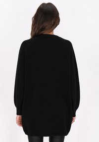 Schwarzer, übergroßer Pullover aus weichem Stoff, mit langen Ärmeln und rundem Halsausschnitt. Glatte Textur mit lockerer Passform.