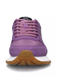 Baskets de sport violettes en daim et en mesh, avec une semelle intermédiaire blanche, une semelle texturée et des lacets plats. "LES FILLES COURENT PLUS VITE" imprimé sur la languette.