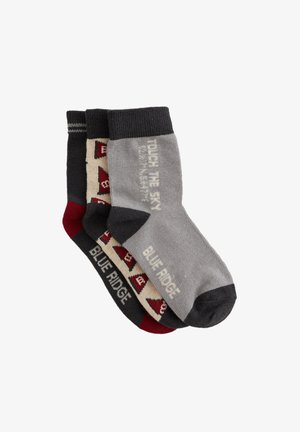 Tři páry krátkých ponožek v šedé, tmavě šedé a burgundské barvě. Vzory zahrnují geometrické designy a text, vyrobené z měkké pleteniny.