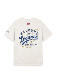 Biała bawełniana koszulka z niebieskim i żółtym napisem graficznym "WELCOME TO LEGANÉS" oraz konturem mapy. Krótkie rękawy z detalem logo na rękawie.