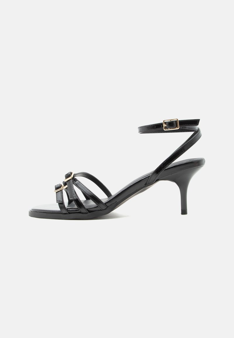Sandale noire en cuir à brides, talon kitten, bout carré, deux boucles devant et bride de cheville avec fermeture à boucle dorée.