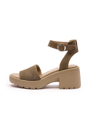 Brązowy zamszowy sandał na wysokim obcasie z masywną platformą i regulowanym paskiem na kostce, z okrągłym, otwartym noskiem oraz teksturowaną gumową podeszwą.