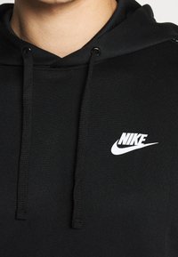 Schwarzer Nike-Hoodie mit glatter Textur, Zugkordelkapuze und einem weißen Nike-Logo auf der linken Brust. Klassisches, sportliches Design.