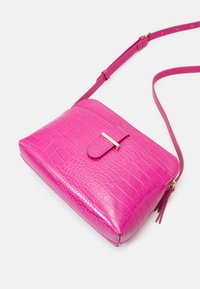 Różowa torebka na ramię z imitacji skóry krokodyla o płaskiej strukturze, z regulowanym paskiem i złotym zapięciem. Gładka tekstura z delikatnym połyskiem.