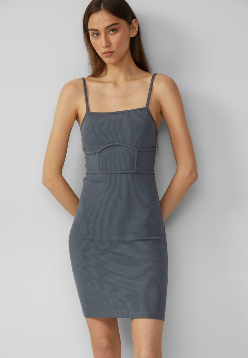 Dunkelgraues, geripptes Bodycon-Kleid mit dünnen Trägern, figurbetontem Schnitt und einer strukturierten Naht im Oberteil, das über das Knie reicht. Glatte Textur.