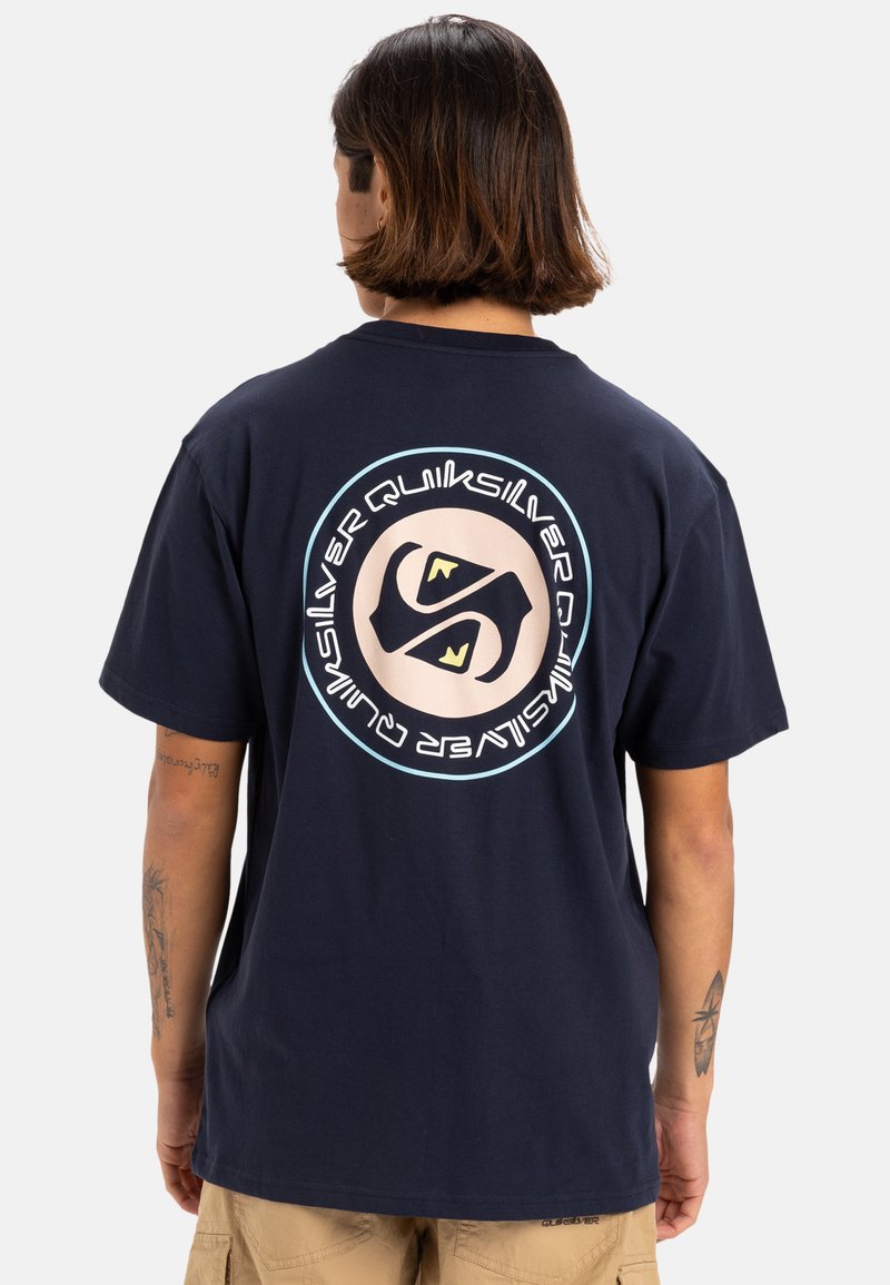 Camiseta de algodón azul marino con un gran logo circular en la parte de atrás que presenta elementos de diseño únicos y un ajuste cómodo y holgado.