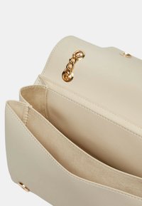 Borsa in eco-pelle beige con un accento in catena dorata, dotata di due scomparti principali e di un morbido rivestimento interno testurizzato.