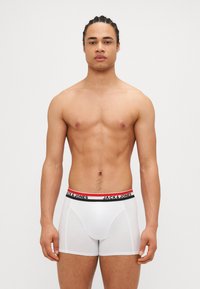Boxers blancs avec une ceinture élastique noire et rouge arborant le logo "JACK & JONES". Fabriqués en matériau doux et extensible.