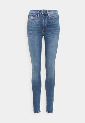 Jean skinny bleu taille haute avec poches avant, passants de ceinture, fermeture par bouton, et effets délavés le long des cuisses et des genoux.