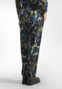 Zwarte joggingsbroek met een meerkleurig, abstract camouflagepatroon in blauw, groen en beige. Bevat een elastische tailleband en boorden, plus zijzakken.