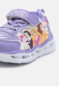 Violet sportbačiai su lipduku, papuošti trims princesių personažų grafikomis. Balta pado apdaila ir tekstūruotas audinys.