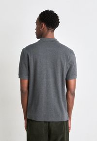Kurzärmliges Poloshirt in Dunkelgrau aus weichem Stoff. Verfügt über einen klassischen Kragen, seitliche Schlitze und eine lockere Passform für hohen Komfort.