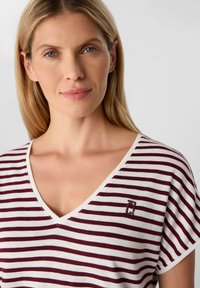 Gestreiftes V-Ausschnitt T-Shirt in Burgunderrot und Weiß, aus weichem Stoff gefertigt. Mit einem gestickten Logo auf der Brust und kurzen Ärmeln.