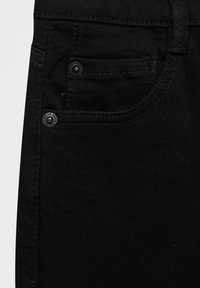 Poche de jean en denim noir avec coutures visibles et deux rivets métalliques, un sur la petite poche à monnaie et un en dessous.
