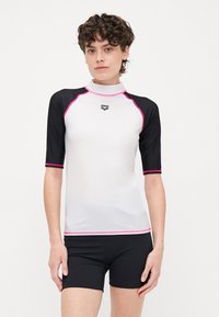 Kortärmad rash guard i vitt och svart med rosa detaljer. Slät, stretchig tyg med hög hals och logotypdetalj på bröstet.
