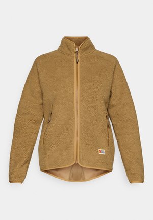 Jachetă din fleece bej, cu guler înalt, fermoar pe toată lungimea frontală și buzunare laterale cu fermoar. Prezintă o suprafață texturată și un tiv contrastant.