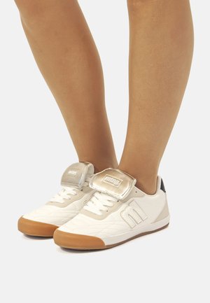 Zapatillas blancas con un diseño texturizado, con acentos grises, una correa plateada brillante y una suela de goma.