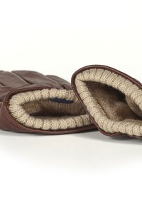 Brune lærhansker med beige ullfôr, med et mykt, strikket mansjett ved håndleddet. Designet inkluderer tydelige fingersegmenter og rene sømmer.