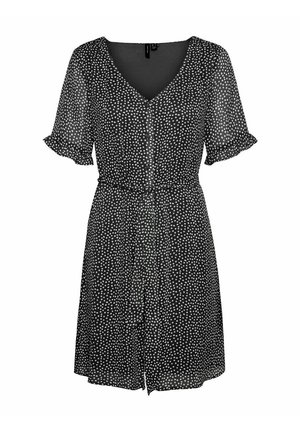 Melnas īsām piedurknēm kleita ar baltām punktiņām, V-veida kakla izgriezums, pogu aizdare un savilkti viduklis. Izgatavota no viegla, caurredzama auduma.