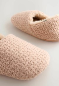 Waffelstrukturiert, pinke Hausschuhe mit einem weichen, mit Fell ausgekleideten Innenraum und einer abgerundeten Zehe. Verfügt über subtile, funkelnde Akzente im gesamten Stoff.