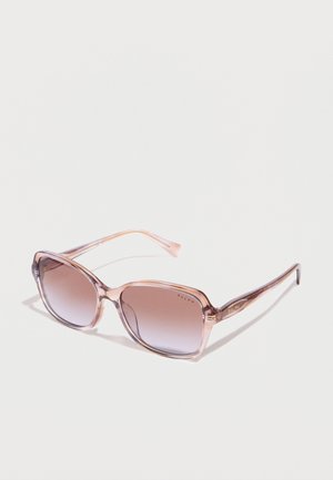 Lunettes de soleil carrées oversize transparentes roses avec verres dégradés marron et inscription « Ralph » sur les branches et le coin du verre.