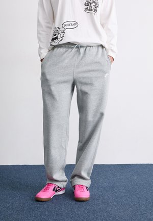 Pantalon de jogging en coton gris avec taille élastique et poches latérales, arborant un petit logo Nike blanc sur la cuisse gauche.