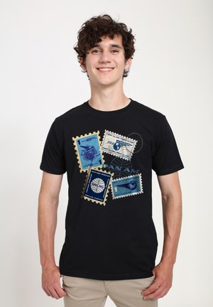 Sort t-shirt med grafisk design af farverige frimærker i blå og beige, med postale motiver og tekstakcenter.